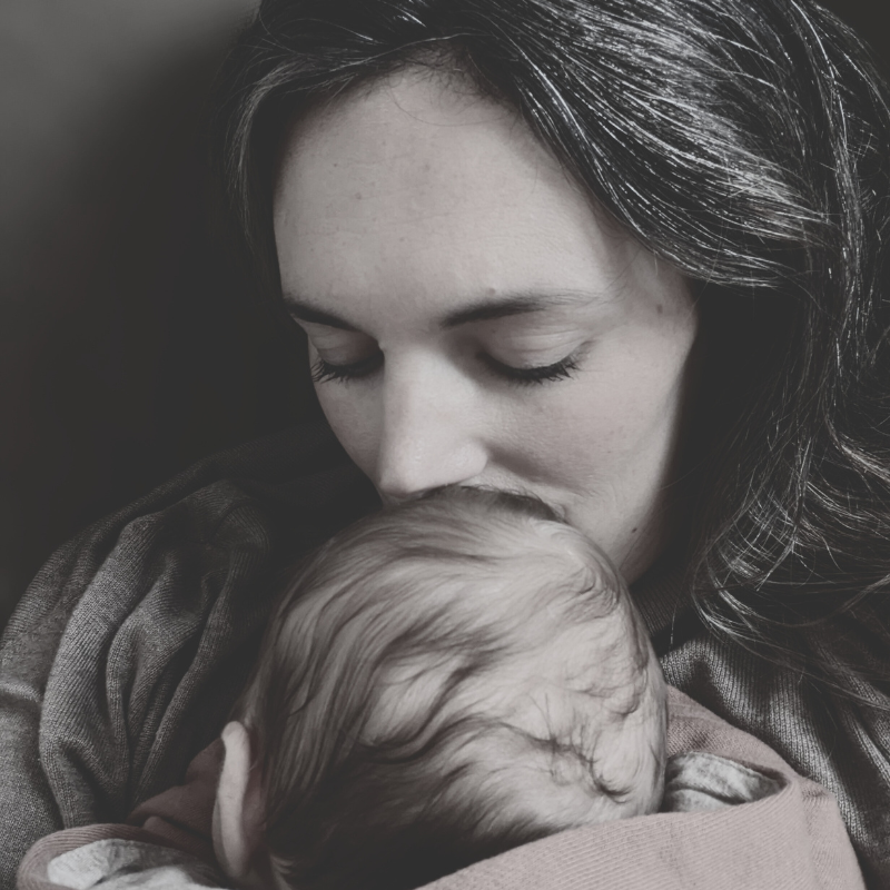 A mother kissing her newborn baby's head